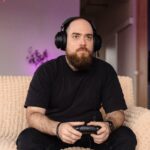 a man in all black outfit sitting on his couch wearing headphones playing the new Clair Obscur game depicting the Expedition 33 community craze