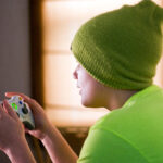 a child in a green cap and green shirt playing 007 First Light on his X Box